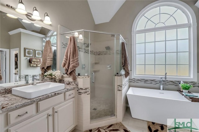 bathroom featuring tile patterned flooring, vaulted ceiling, vanity, and plus walk in shower