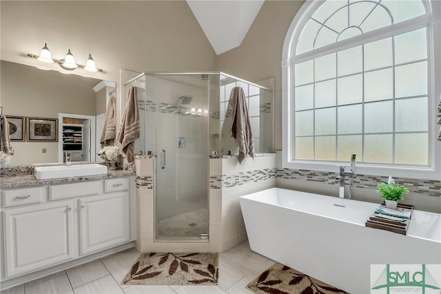 bathroom featuring separate shower and tub, vanity, vaulted ceiling, and tile patterned flooring