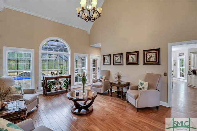 living room with a wealth of natural light, a chandelier, hardwood / wood-style floors, and high vaulted ceiling