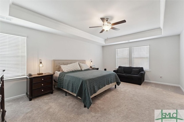 carpeted bedroom with ceiling fan, a tray ceiling, and multiple windows