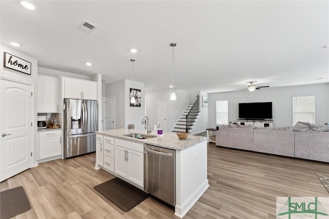 kitchen featuring decorative light fixtures, sink, a kitchen island with sink, appliances with stainless steel finishes, and white cabinets