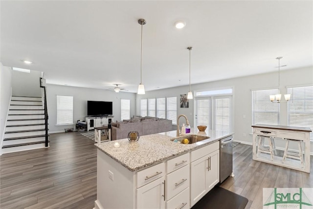 kitchen featuring dishwasher, a center island with sink, sink, white cabinets, and ceiling fan with notable chandelier