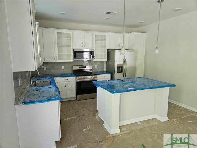 kitchen with visible vents, decorative backsplash, a kitchen island, white cabinets, and appliances with stainless steel finishes