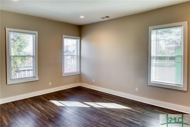 empty room featuring dark hardwood / wood-style flooring and plenty of natural light