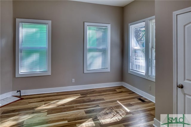 empty room with plenty of natural light and hardwood / wood-style floors