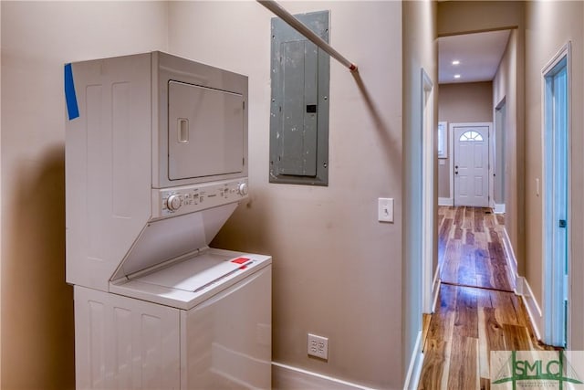 washroom featuring stacked washer / dryer, light hardwood / wood-style floors, and electric panel