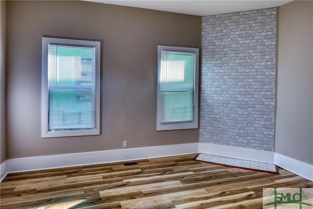 empty room with hardwood / wood-style flooring and plenty of natural light