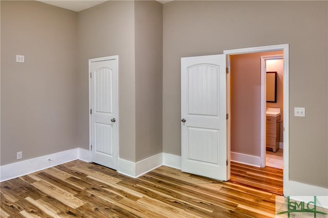 unfurnished bedroom featuring ensuite bath and hardwood / wood-style flooring