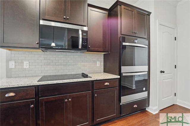 106 Liam Ct, Guyton, GA 31312 - kitchen featuring stainless steel microwave, black electric cooktop, double wall oven, wood finished floors, and decorative backsplash