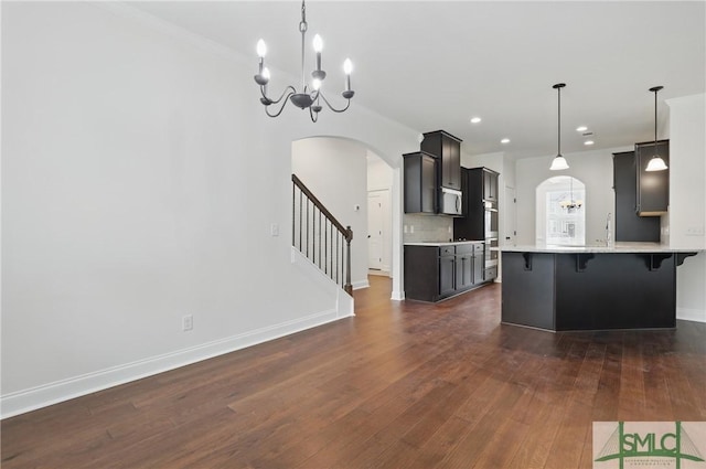 106 Liam Ct, Guyton, GA 31312 - kitchen with stainless steel appliances, arched walkways, a kitchen breakfast bar, dark wood finished floors, and light countertops