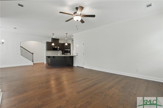 106 Liam Ct, Guyton, GA 31312 - unfurnished living room with arched walkways, a ceiling fan, dark wood-style flooring, baseboards, and stairs