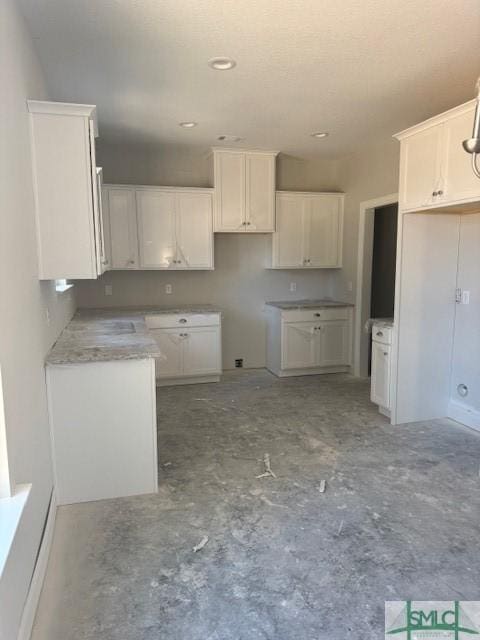 kitchen featuring concrete floors and white cabinetry