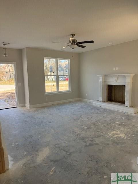 unfurnished living room with plenty of natural light, a premium fireplace, baseboards, and concrete flooring