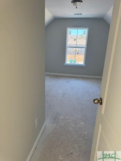 additional living space with lofted ceiling, baseboards, and visible vents