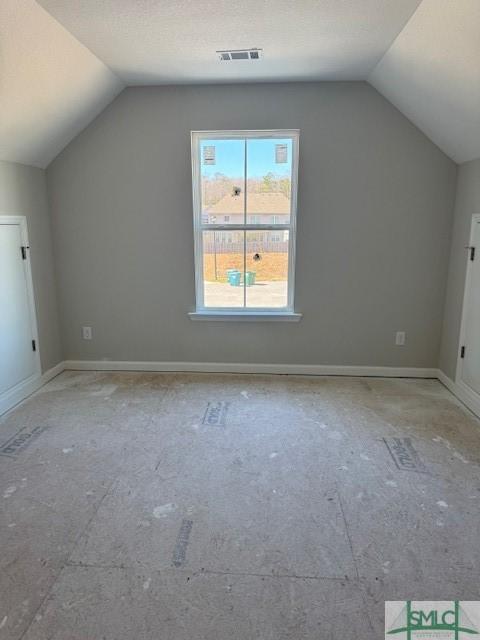 additional living space featuring lofted ceiling, visible vents, and baseboards