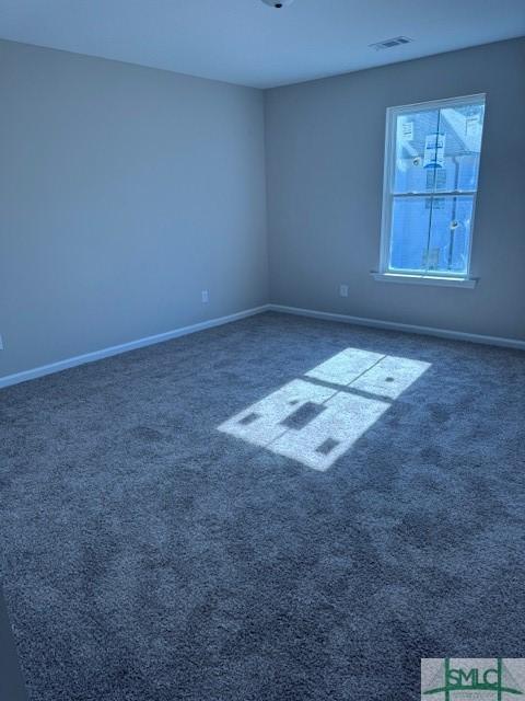 spare room featuring dark colored carpet