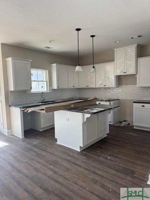 kitchen with pendant lighting, white cabinets, a center island, and dark hardwood / wood-style flooring