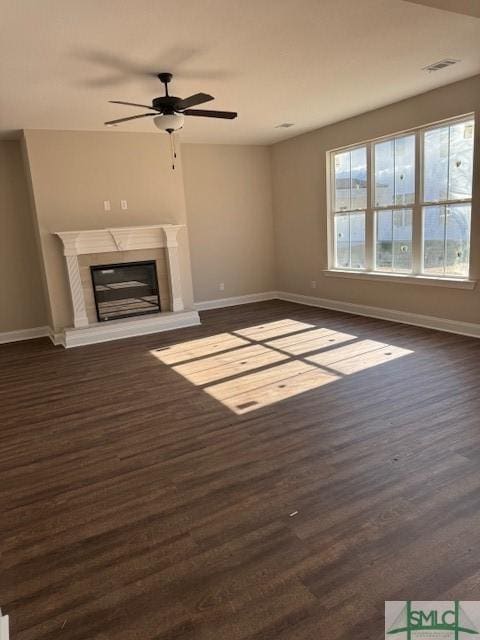 unfurnished living room with ceiling fan, a wealth of natural light, a high end fireplace, and dark hardwood / wood-style flooring