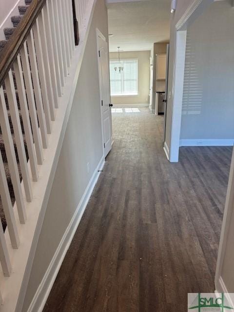 corridor featuring stairs, dark wood-style flooring, and baseboards