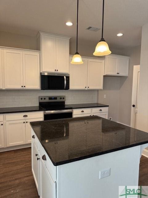 kitchen with stainless steel appliances, pendant lighting, white cabinetry, and dark stone countertops