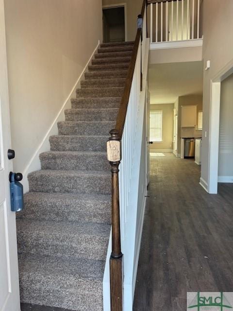 stairway with a high ceiling, baseboards, and wood finished floors