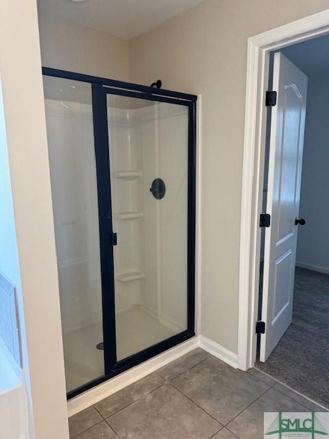 full bath with a stall shower, baseboards, and tile patterned floors