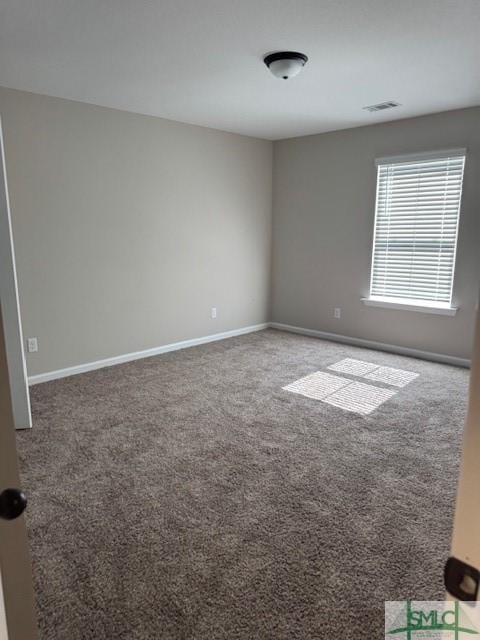 empty room featuring carpet flooring, visible vents, and baseboards