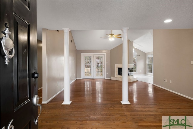 unfurnished living room featuring dark hardwood / wood-style floors, ceiling fan, a textured ceiling, and a tiled fireplace