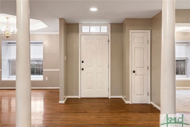 entrance foyer with a textured ceiling, dark hardwood / wood-style flooring, crown molding, and a notable chandelier