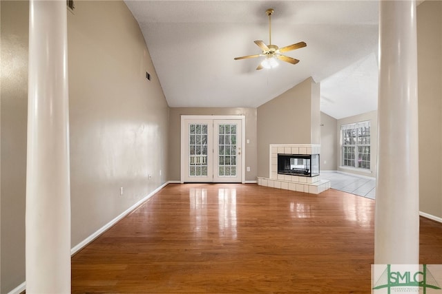 unfurnished living room with ceiling fan, wood-type flooring, lofted ceiling, and a tiled fireplace