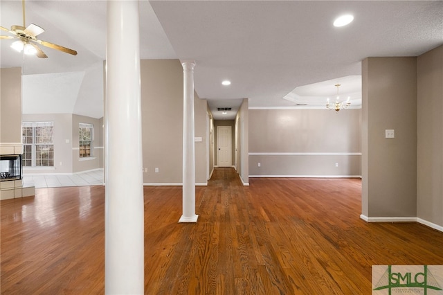 interior space with wood-type flooring, ornate columns, a notable chandelier, vaulted ceiling, and crown molding