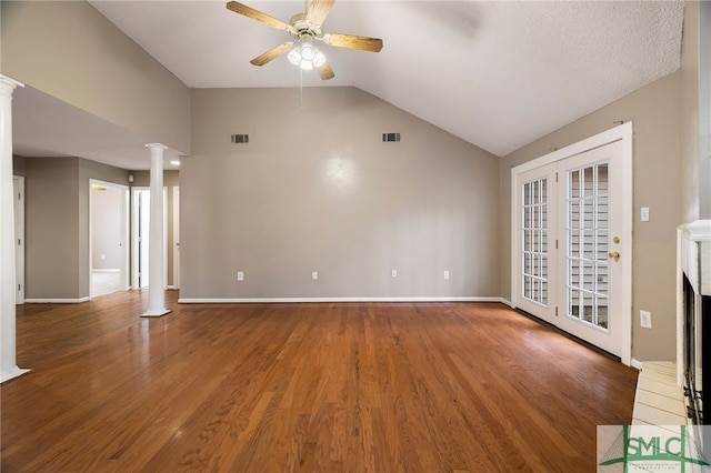 unfurnished living room with ceiling fan, vaulted ceiling, a fireplace, hardwood / wood-style floors, and decorative columns