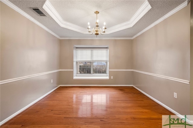 unfurnished room featuring hardwood / wood-style flooring, a tray ceiling, a notable chandelier, a textured ceiling, and crown molding