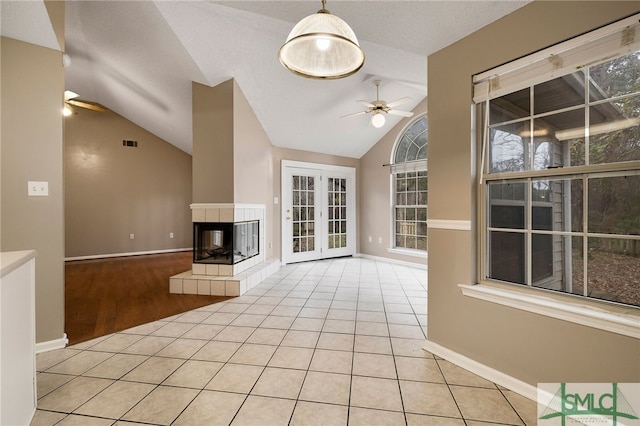 unfurnished living room featuring vaulted ceiling, ceiling fan, light tile patterned floors, and a fireplace