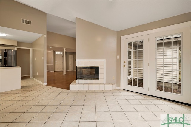 unfurnished living room featuring a tiled fireplace and light tile patterned flooring