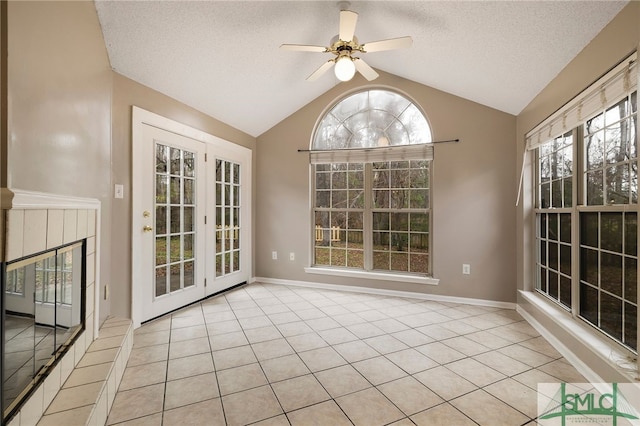 unfurnished sunroom with vaulted ceiling, ceiling fan, and a tile fireplace