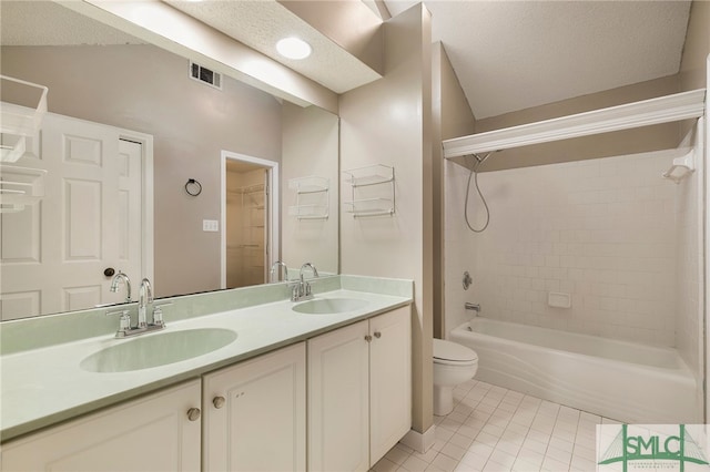 full bathroom with a textured ceiling, tiled shower / bath, tile patterned floors, vanity, and toilet