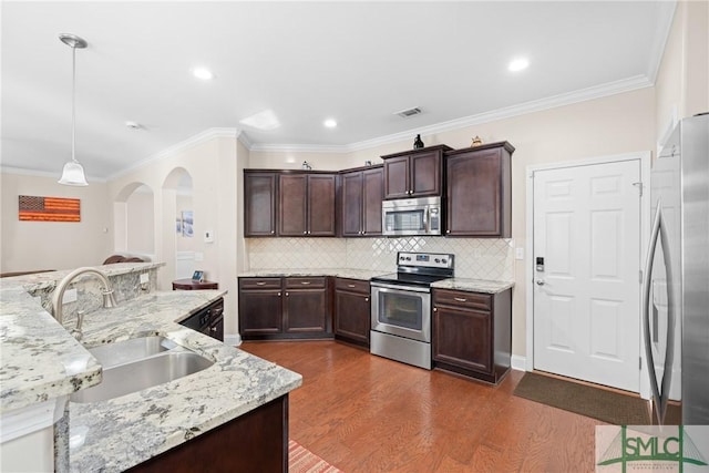 kitchen with sink, light stone counters, hanging light fixtures, dark hardwood / wood-style floors, and stainless steel appliances