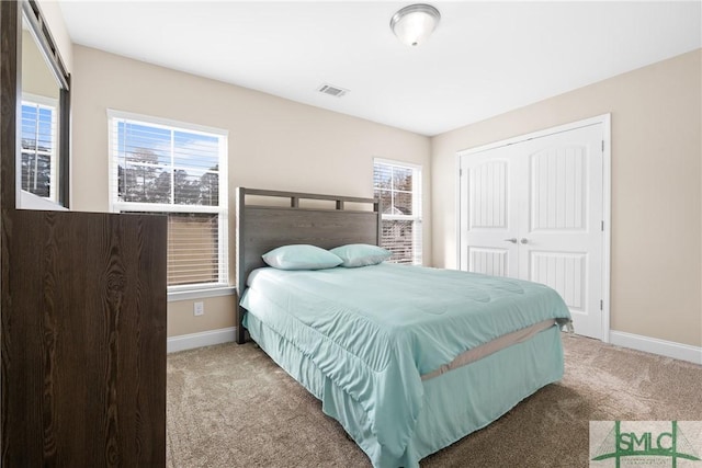 carpeted bedroom featuring multiple windows and a closet