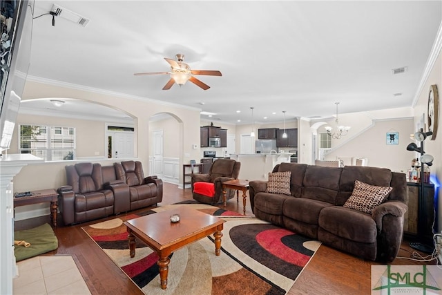 living room featuring ornamental molding, ceiling fan with notable chandelier, and light hardwood / wood-style flooring