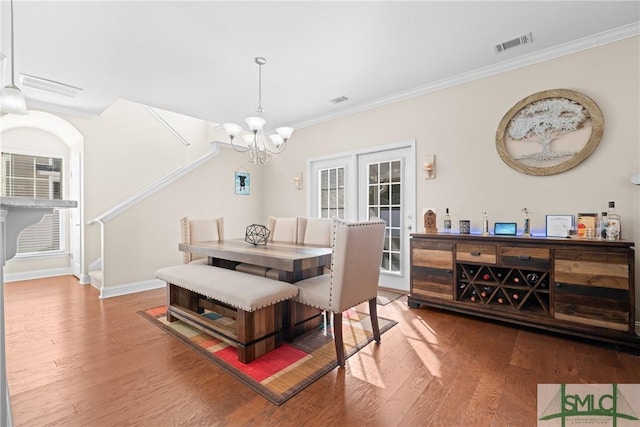 dining room with hardwood / wood-style flooring, ornamental molding, a wealth of natural light, and a notable chandelier