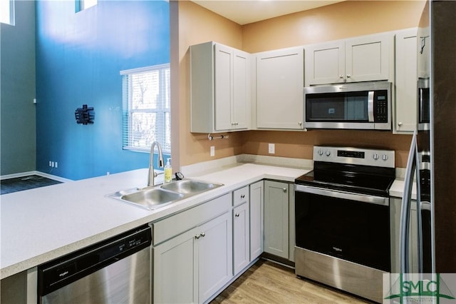 kitchen with light wood-type flooring, sink, stainless steel appliances, and white cabinetry