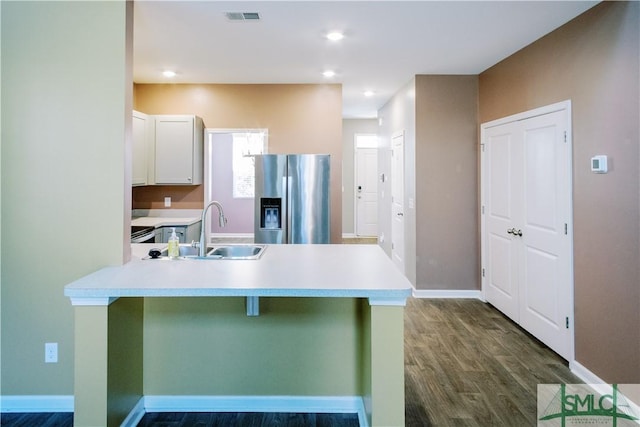 kitchen with stainless steel fridge with ice dispenser, kitchen peninsula, white cabinets, a breakfast bar, and sink