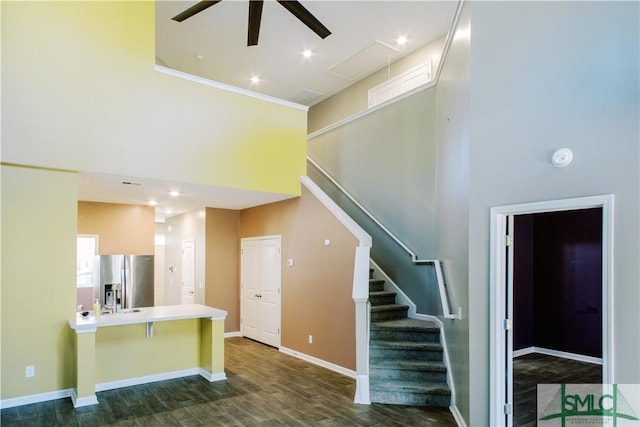 staircase featuring ceiling fan, a high ceiling, and hardwood / wood-style floors