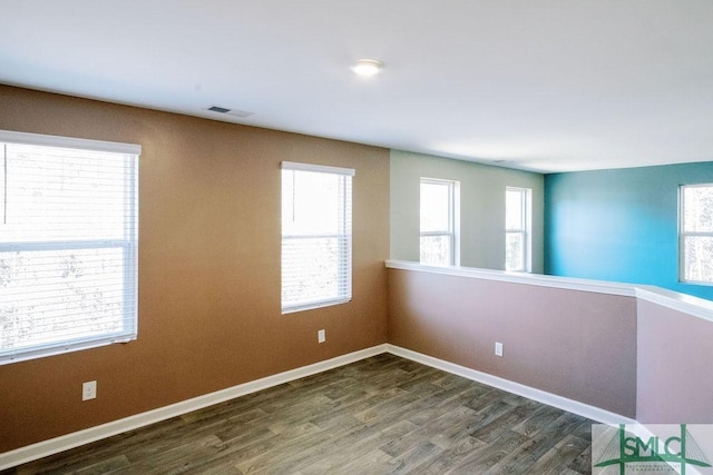 empty room featuring dark wood-type flooring and a wealth of natural light