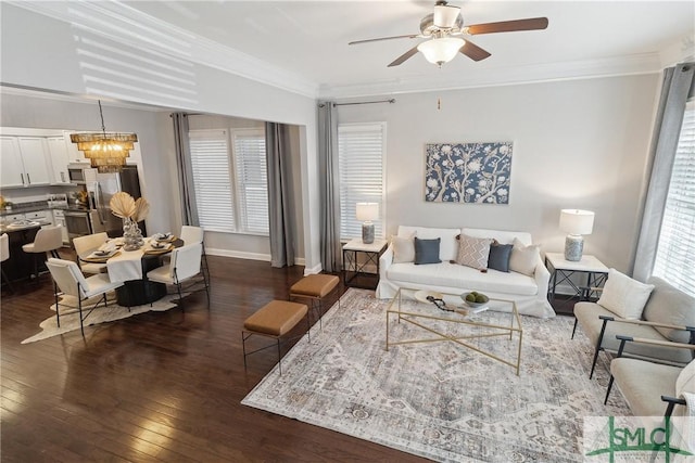 living room featuring dark wood-type flooring, ceiling fan with notable chandelier, and ornamental molding