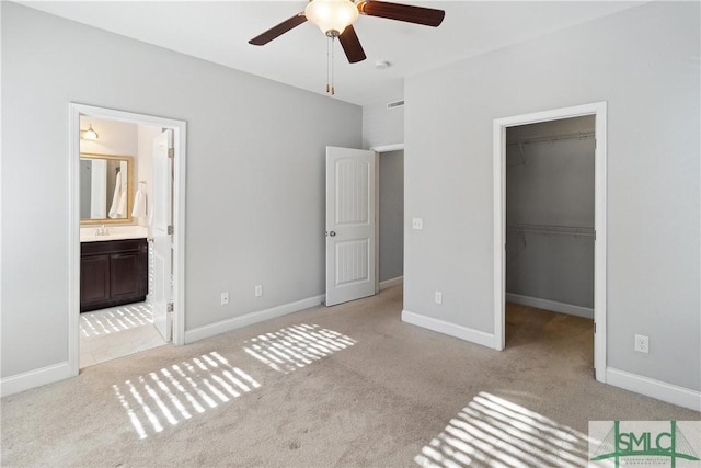 unfurnished bedroom with a spacious closet, a closet, ensuite bathroom, and ceiling fan