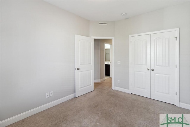 unfurnished bedroom with a closet and light carpet