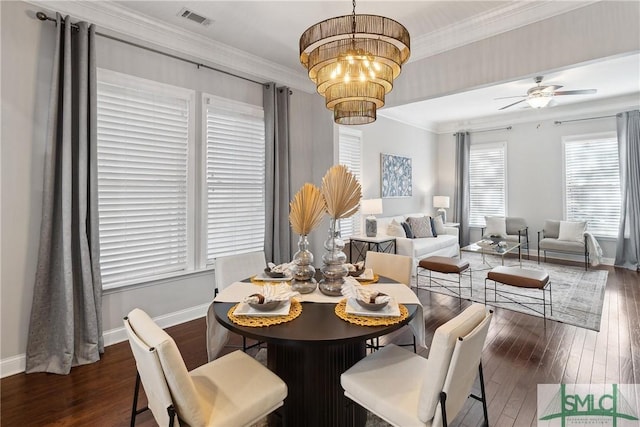 dining room with dark wood-type flooring, ornamental molding, and ceiling fan with notable chandelier