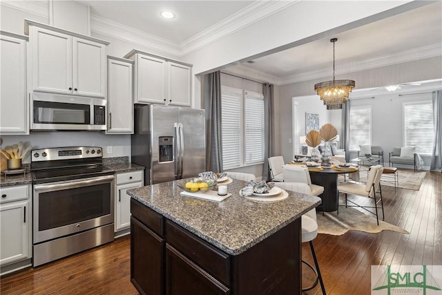 kitchen featuring dark stone countertops, hanging light fixtures, dark wood-type flooring, stainless steel appliances, and a chandelier